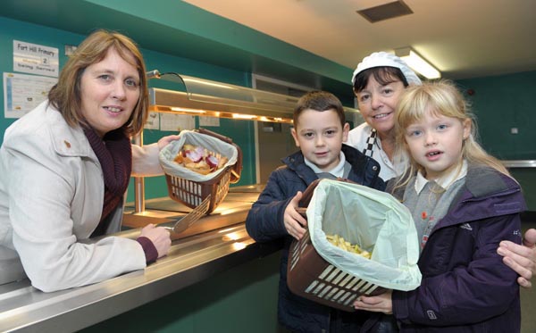 Lisburn councils Jenny Palmer, left, promotes brown bin kitchen caddies for EWWR alongside meals supervisor Karen Brown pupils and from Forthill primary school